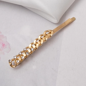 Gold chain hair clip with sparkling rhinestones shown on an elegant white silk background