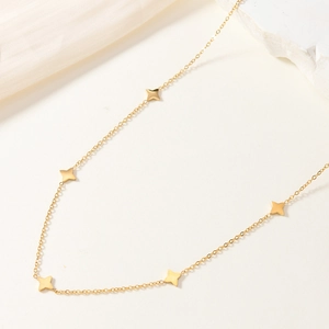 Collana minimalista dorata con stelle a quattro punte su sfondo elegante e moderno