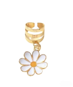 Détail d'un ear cuff doré avec un pendentif marguerite blanche sur un fond blanc pur