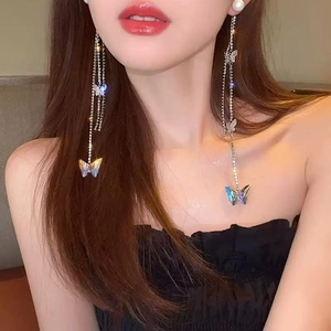 Silver tassel earrings with pearls and iridescent butterflies shown on a model
