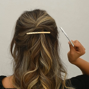 Détail de la texture martelée à la main sur les longues pinces à cheveux en métal doré et argenté