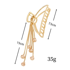 Détail d'une pince à cheveux dorée avec des glands de 15 cm et des perles de champagne