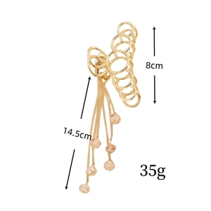 Détail d'une grande pince à cheveux papillon dorée avec dimensions et pompons perles