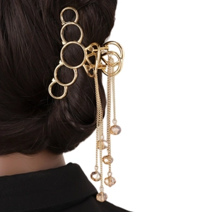 Gros plan d'une pince à cheveux dorée avec glands et perles de cristal ambré sur cheveux
