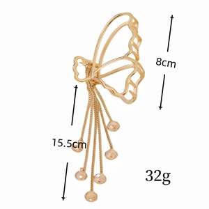 Pince à cheveux papillon dorée élégante avec ailes évidées et longs glands perlés