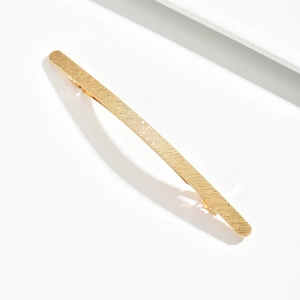 Minimalist gold zinc alloy hair clip with elegant diagonal wave pattern on white surface