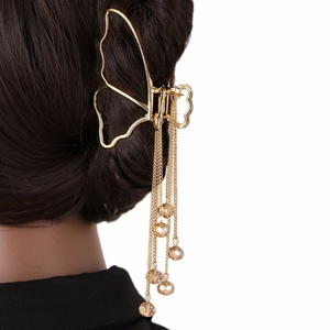 Détail d'une pince à cheveux papillon dorée avec de longues chaînes à glands en cristal