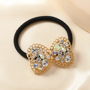 Elegante elastico nero per capelli con fiocco dorato e strass su sfondo di seta