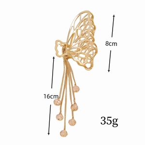 Détail de la pince à cheveux papillon dorée avec pompon, hauteur 8 cm et longueur 16 cm