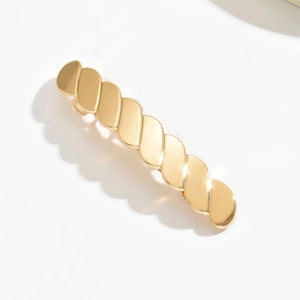 Detail of a large gold alloy hair claw clip with twisted minimalist metal design