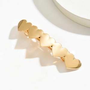 Detail view of the golden alloy heart hair clip with polished metallic finish