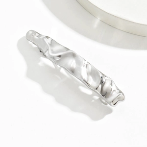 Detailed view of silver hair claw clip featuring liquid metal wavy texture and metallic finish