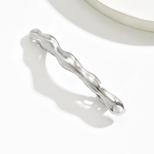 Macro shot of minimalist silver wavy hair claw clip with polished high-gloss mirror finish