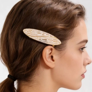 Close-up of elegant gold hair clip featuring intricately embedded white pearls on hair