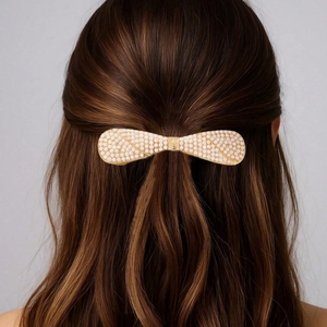 Elegant bow-shaped hair clip with white pearls on gold metal base worn on long hair