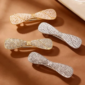 Detailed view of four rhinestone and pearl bow hair clips in gold and silver finishes