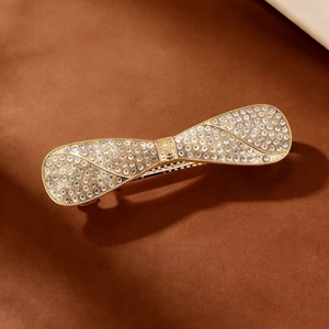 Close-up of sparkling bow hair clip with rhinestones on a golden metal base