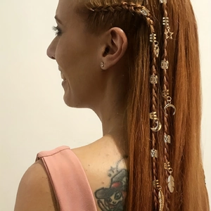 Gros plan d'anneaux de cheveux dorés avec breloques étoile, lune et plume pour tresses