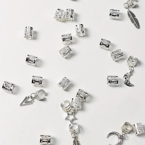 Détail de bijoux de tresse argentés avec pendentifs étoile, lune et feuille sur blanc