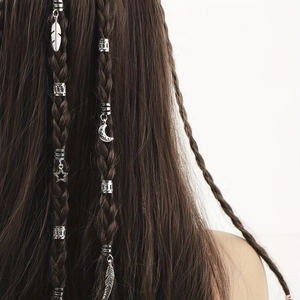 Détail de bijoux de cheveux argentés avec pendentifs plume et étoile sur des tresses