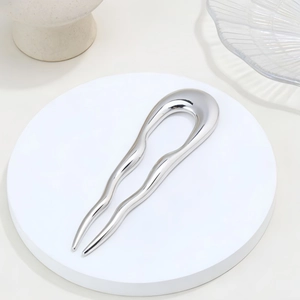 Elegant silver U-shaped hair pin with wavy metallic design on a minimalist display