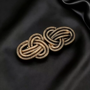 Elegant vintage alloy knot hair clip in gold finish on black silk background