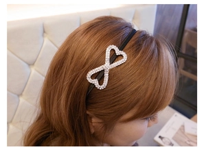 Detail of a thin black headband featuring interlocking hearts with sparkling rhinestones