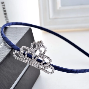 Detail of navy blue satin headband featuring a sparkling rhinestone crown ornament