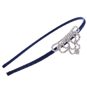Close-up of sparkling rhinestone crown detail on a navy blue satin fabric headband