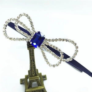 Macro shot of rhinestone bow headband with deep blue emerald-cut gem and fabric wrap