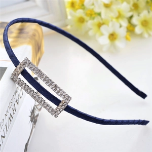Detail of slim navy blue satin headband with shimmering rectangular rhinestone buckle accent