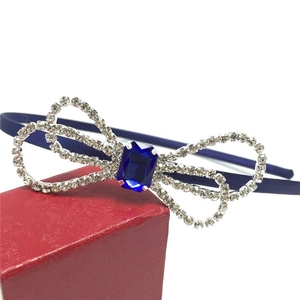 Detail of blue satin headband featuring a large rhinestone bow and center blue gemstone