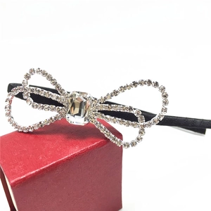 Detail of a black headband with a large rhinestone bow on a red jewelry box