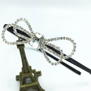 Detail shot of a black rhinestone headband with a large sparkling crystal bow on a white background