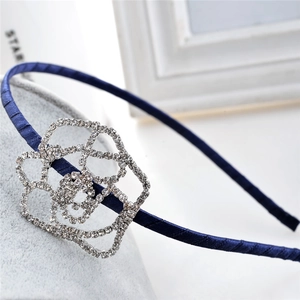 Close-up of sparkling rhinestone camellia flower on a navy blue satin headband