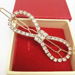 Detail of infinity symbol hair clip with sparkling rhinestones on golden metal base