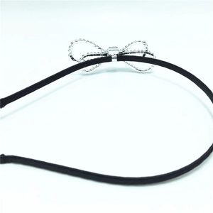Close-up detail of a black headband featuring a sparkling silver crystal bow ornament