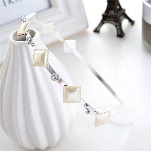 Detail of thin silver headband with pearls and crystals hanging on a white ceramic vase