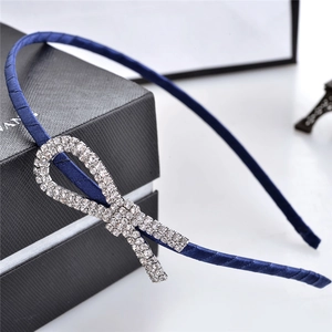 Detailed close-up of dark blue satin headband with sparkling rhinestone bow knot