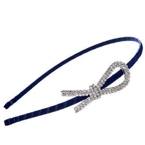 Detail of navy satin headband with a sparkling rhinestone bow on a white background