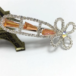Makro-Detail einer silbernen Haarspange mit orangen Kristallen und Strass-Blumenmuster