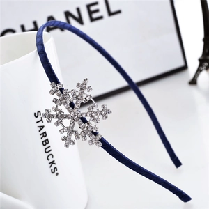 Close-up of navy blue satin headband with a sparkling snowflake rhinestone ornament