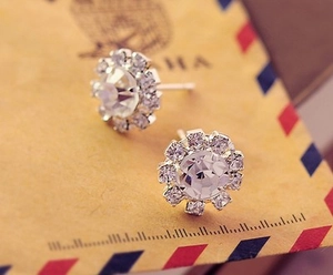 Gros plan de boucles d'oreilles tournesol en argent et zircons sur papier vintage