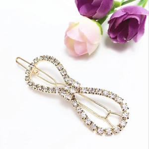 Detailed macro view of a gold bow hair clip with sparkling rhinestones and metal base