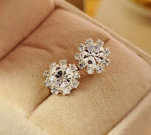 Vue macro de boucles d'oreilles tournesol en argent avec zircon central et halo