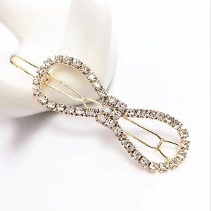 Detail of infinity gold hair clip with sparkling rhinestones on a white surface