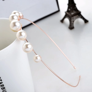 Elegante diadema de oro rosa con perlas degradadas sobre fondo de taza de porcelana blanca