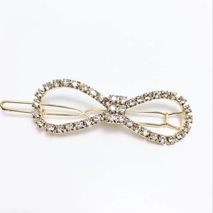 Macro detail of a golden bow hair clip featuring sparkling clear rhinestones for women