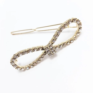 Macro detail of elegant gold bow hair clip featuring sparkling rhinestones and alloy finish
