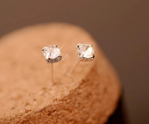 Macro shot of silver square stud earrings with sparkling crystals in four-prong setting